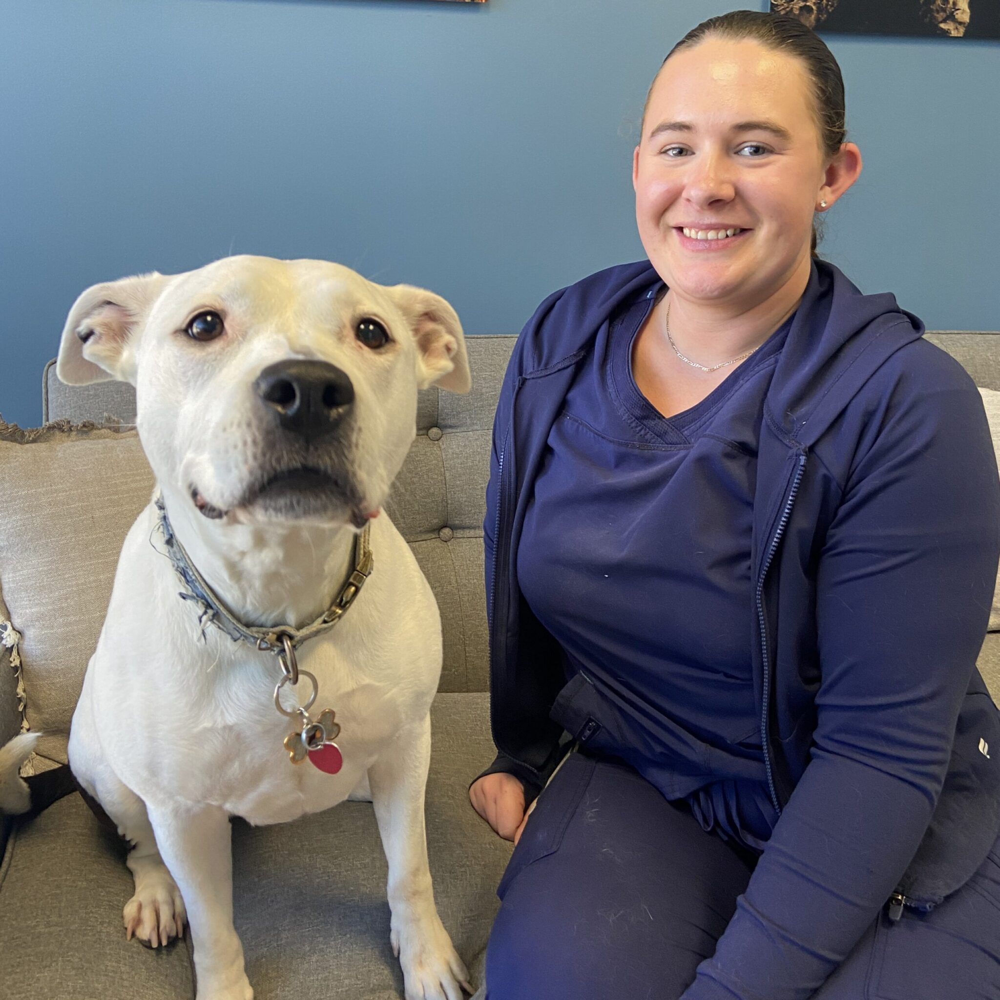 smiling woman sitting next to a white dog